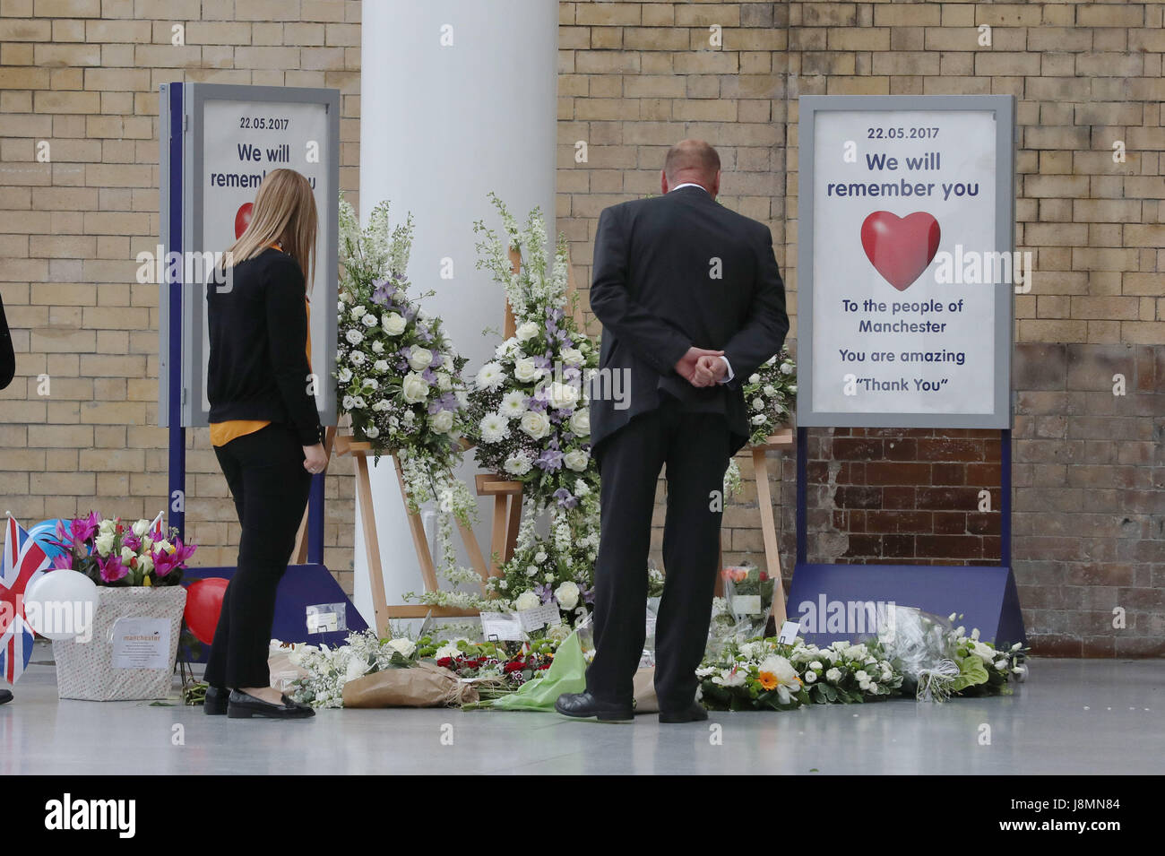 People look at floral tributes at Manchester Victoria railway station which has reopened for the first time since the terror attack on the adjacent Manchester Arena. Stock Photo