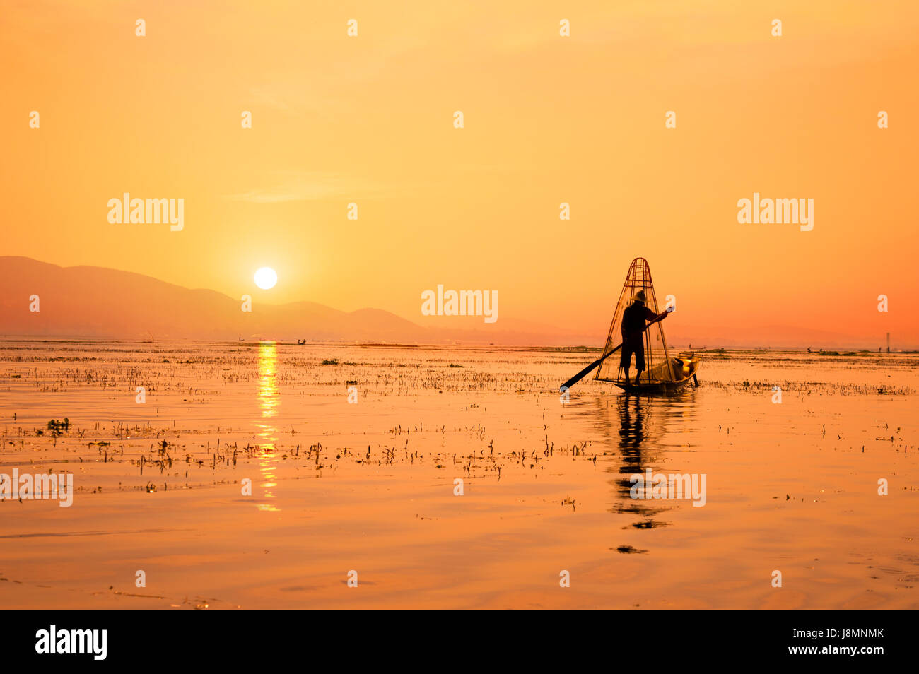 Silhouette of a Burmese fisherman on bamboo boat at sunset. Inle lake ...