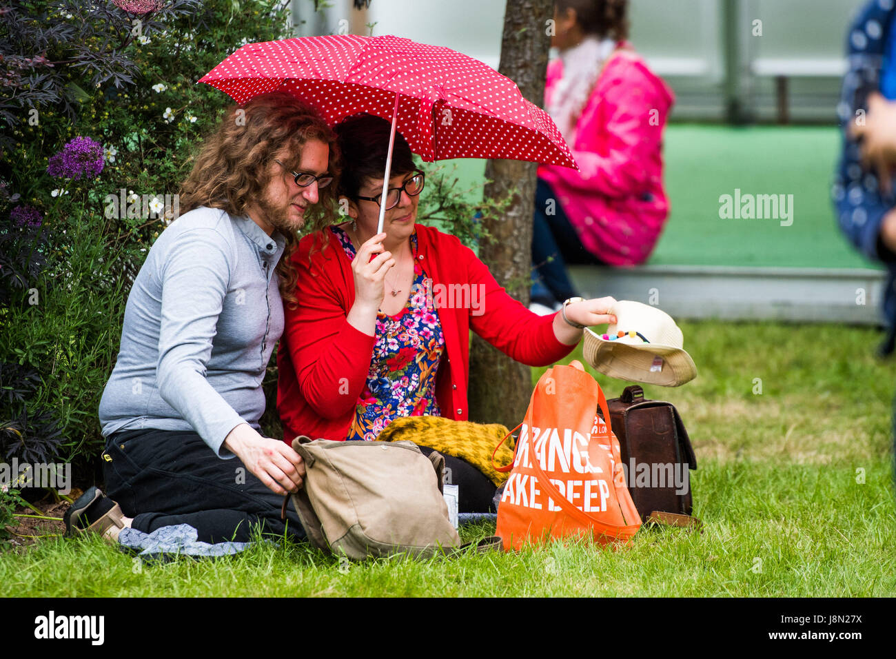 Hay Festival, Wales UK, Monday 29 May 2017 A happy couple share a picnic under theur umbrella in the light rain at the 2017 Hay Literature Festival Now in its 30th year, the festival draws tens of thousand of visitors a day to what was described by former US president Bill Clinton as 'the woodstock of the mind' Photo credit Credit: Keith Morris/Alamy Live News Stock Photo