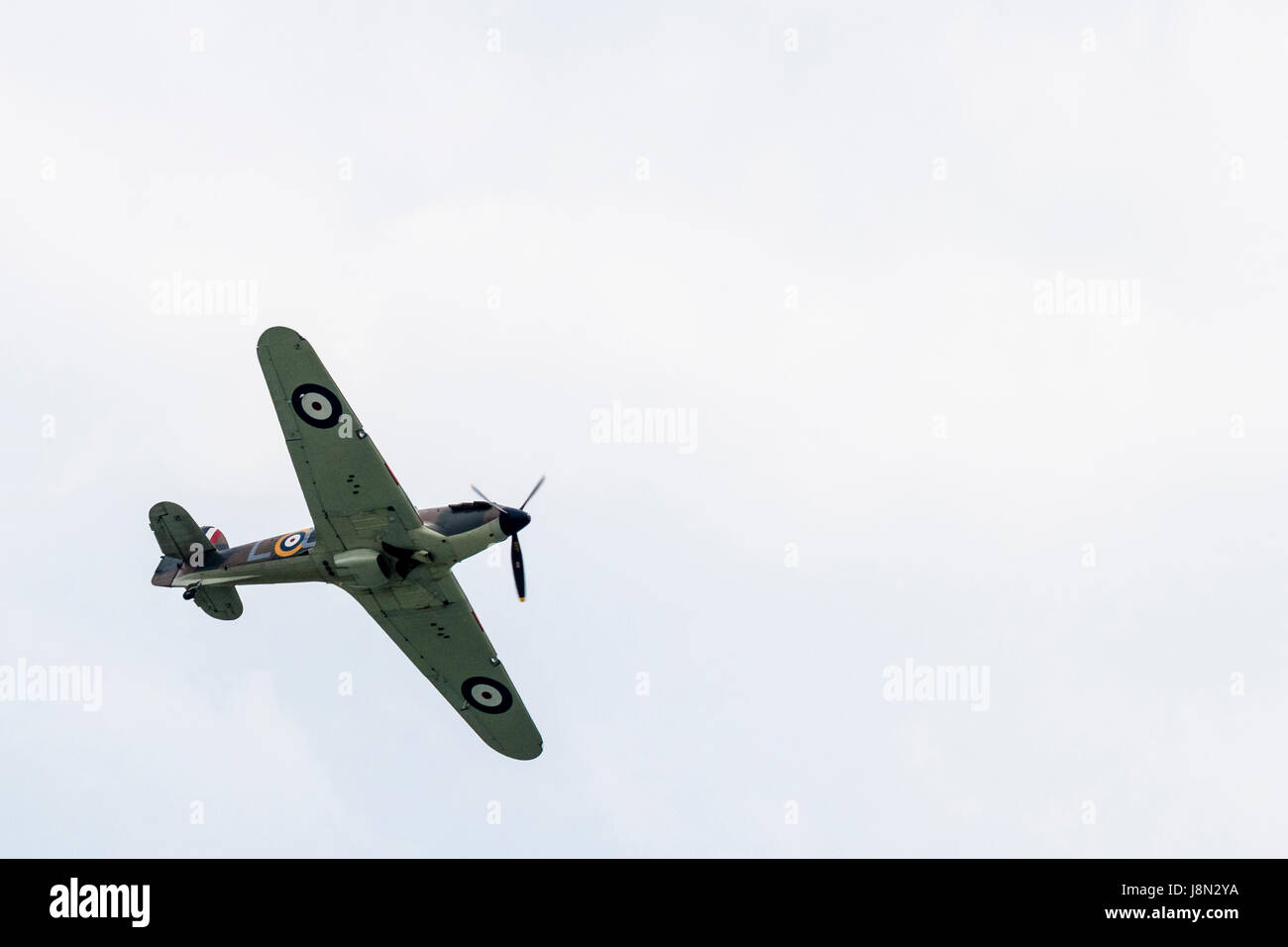 World war two vintage fighter plane, Hawker Hurricane flying overhead against a pale white and blue sky. Stock Photo