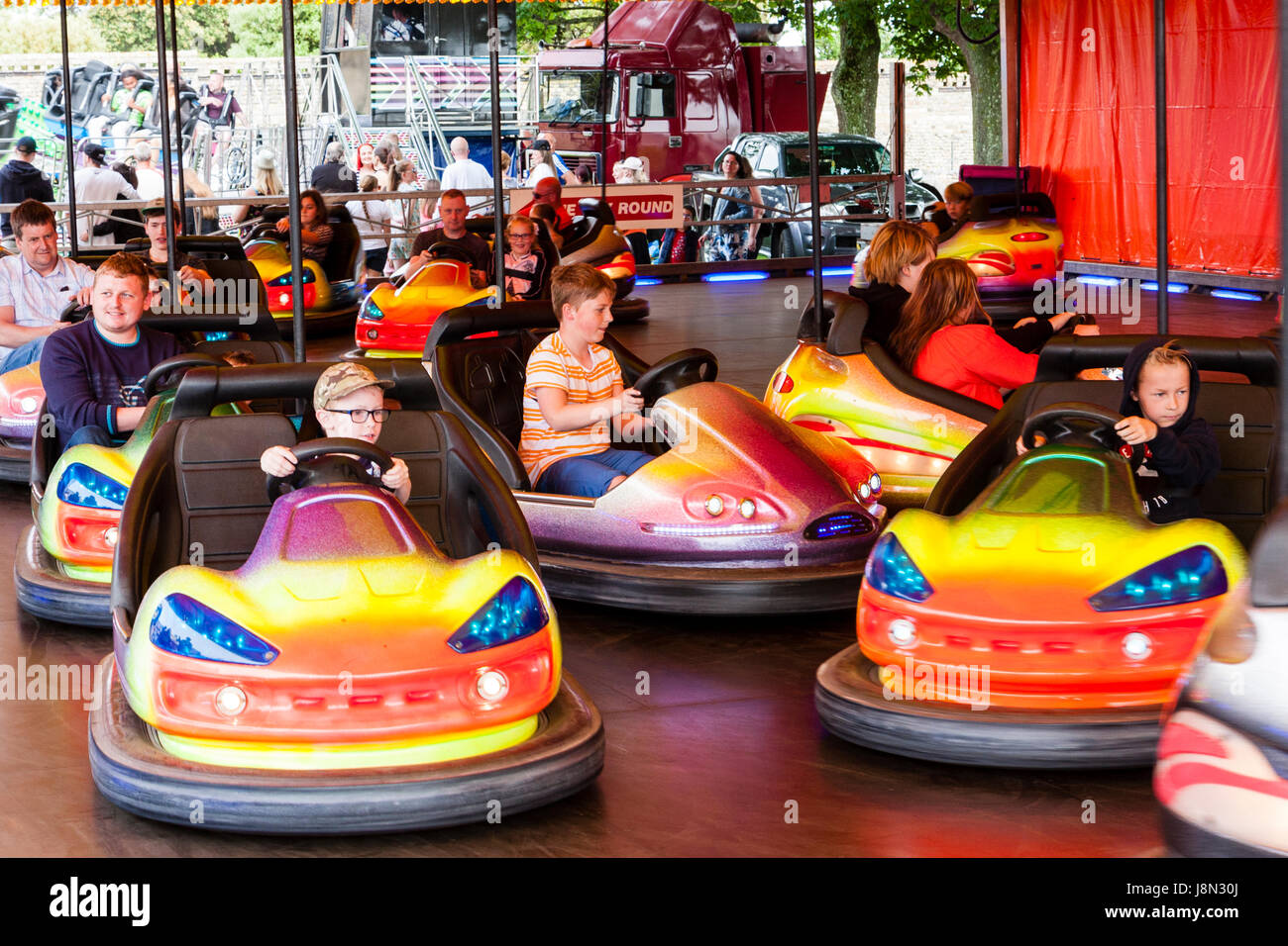 Brightly coloured dodgem cars being driven and bumped by mainly children at seaside funfair at Ramsgate. Stock Photo