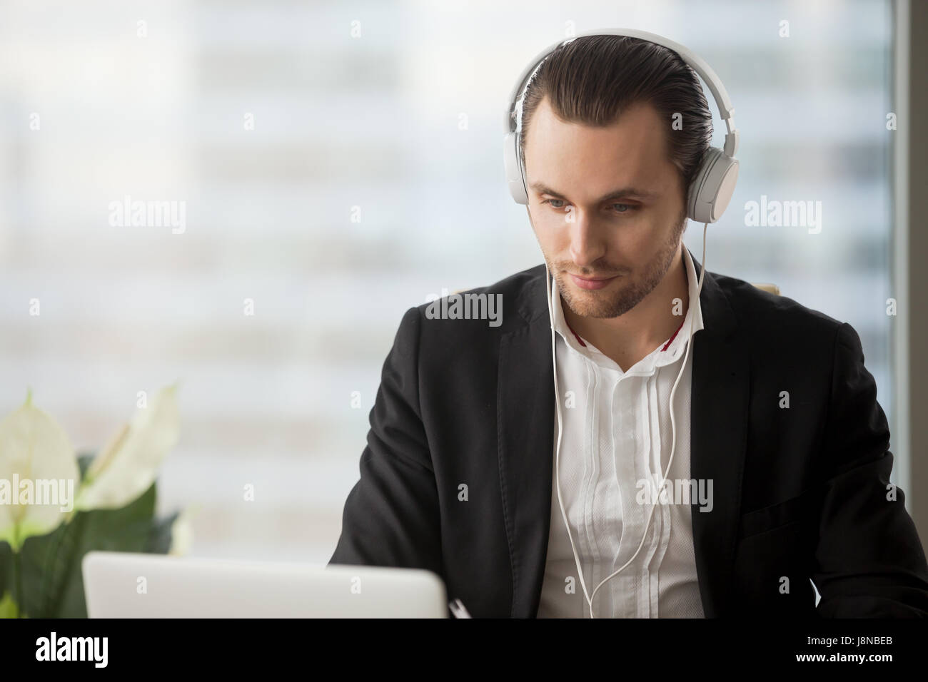 Young man in headphones listening music while working on laptop in ...