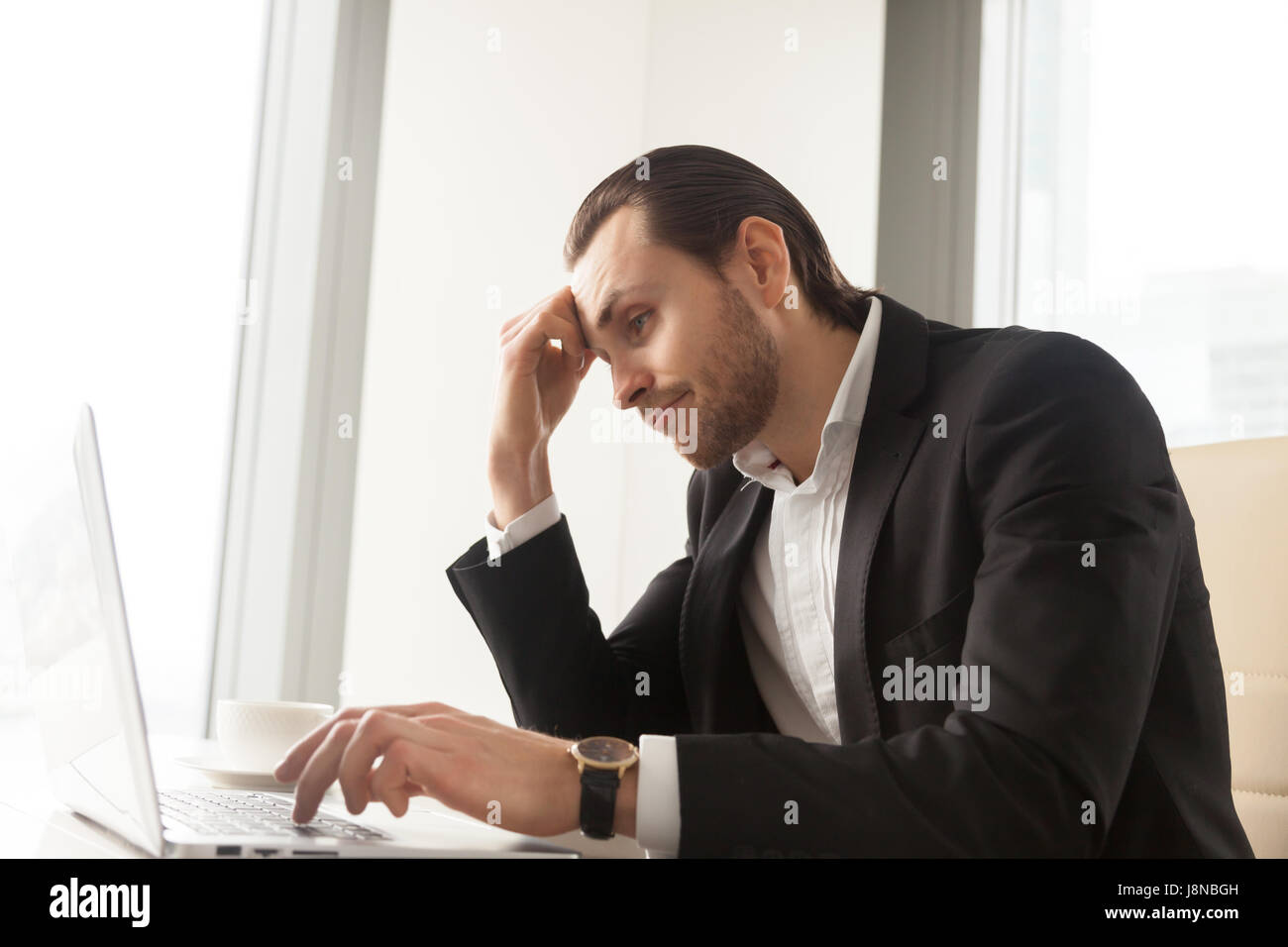 Young businessman at desk tired from routine laptop work. Entrepreneur