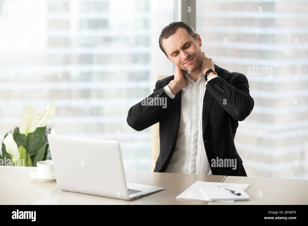 Businessman massaging his tense neck muscles Stock Photo
