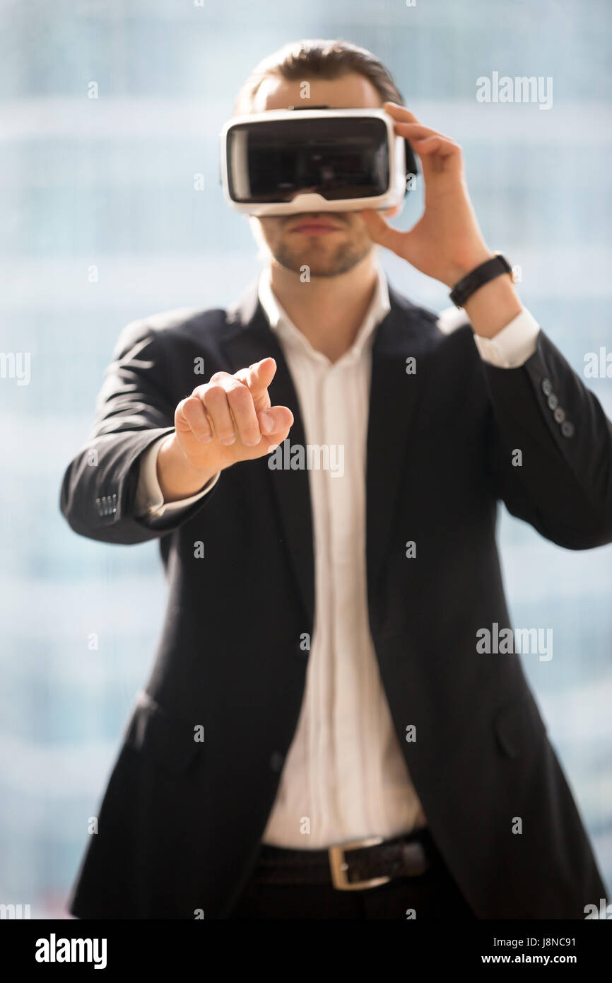 Businessman wearing VR glasses and touching air Stock Photo - Alamy