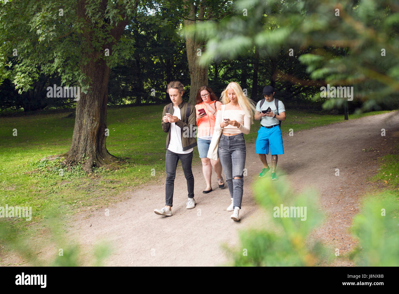 Group of friends playing augmented reality game with mobile phones in park Stock Photo