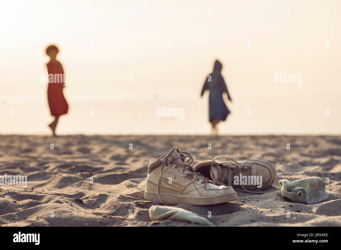 Two women standing on beach, shoes in foreground Stock Photo