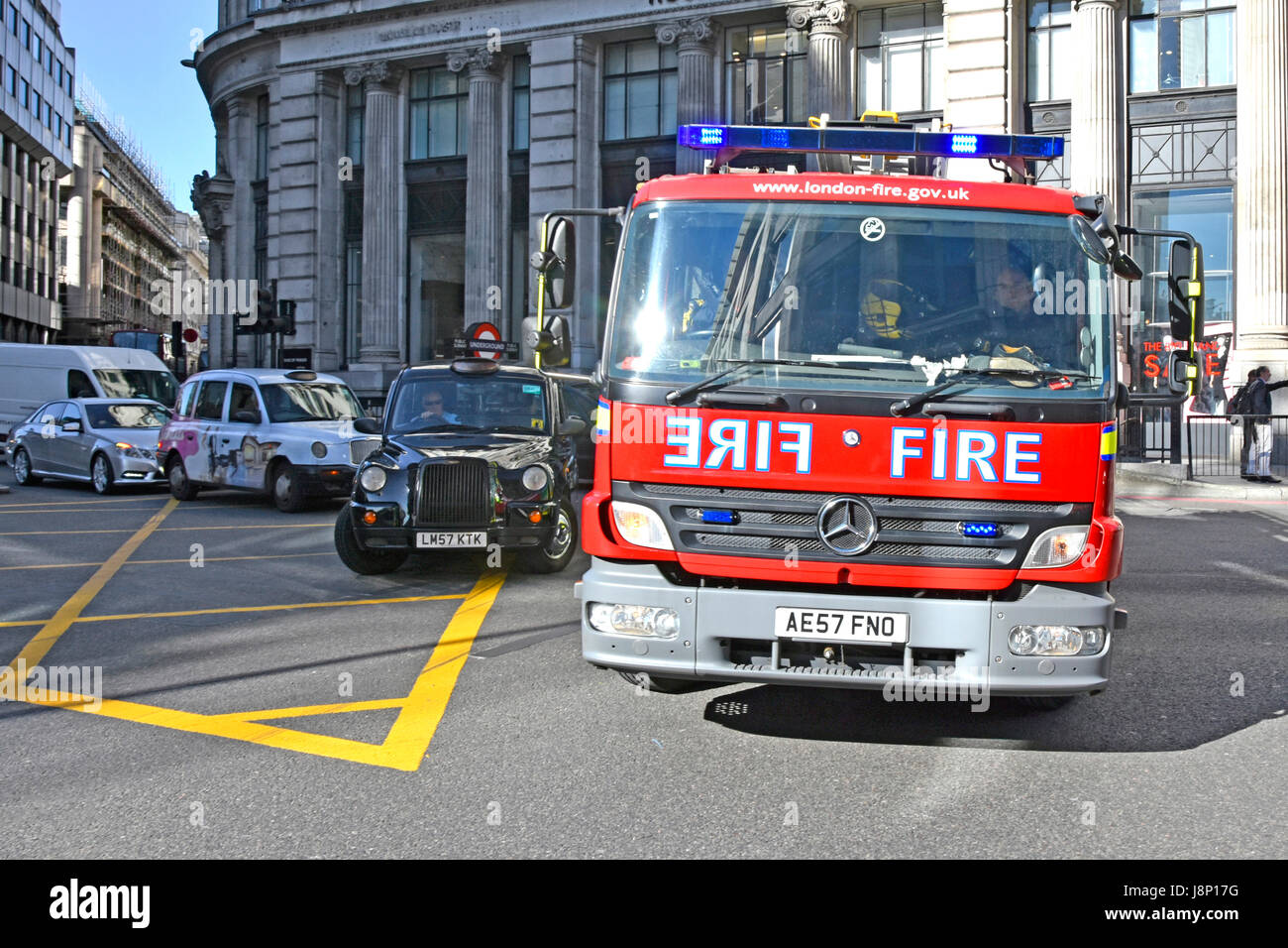 Close up Fire engine emergency services response City of London UK Fire brigade Mercedes Benz appliance 999 call passing London taxi at box junction Stock Photo