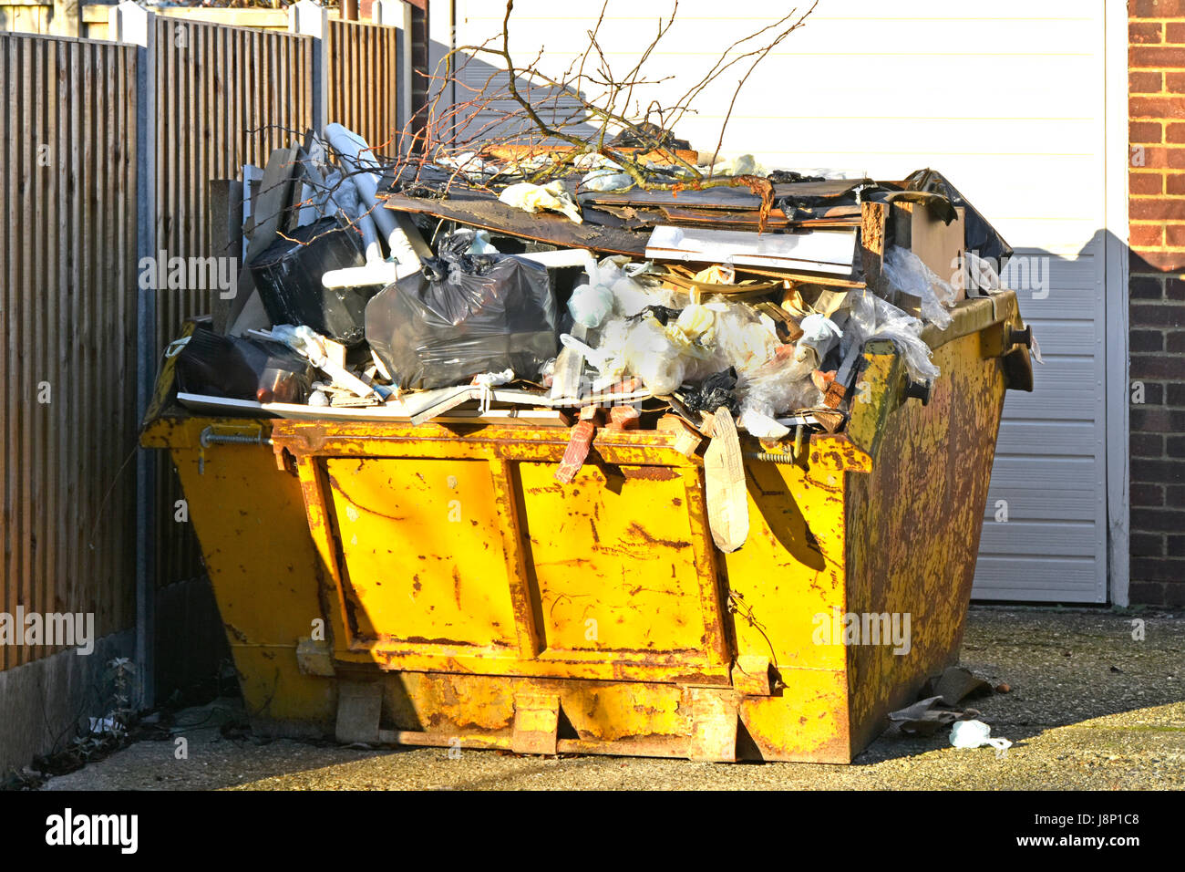 Full UK skip bin rubbish uk waste management logistics garbage trash overflowing awaiting moving to landfill from domestic property after clearout Stock Photo