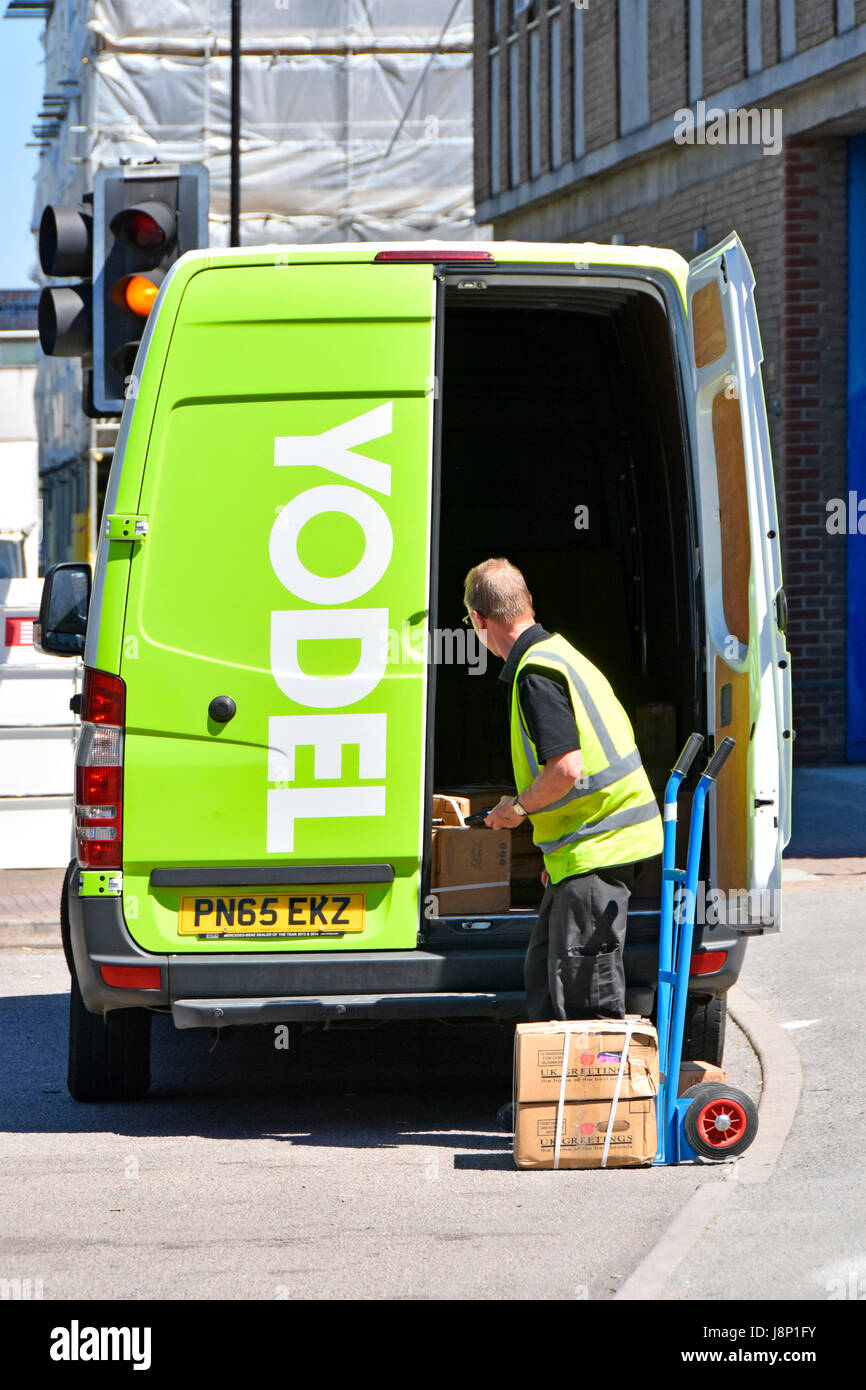 Yodel logistics services transporting & delivery van driver unloading parcels onto trolley as part of national UK supply chain delivering process Stock Photo