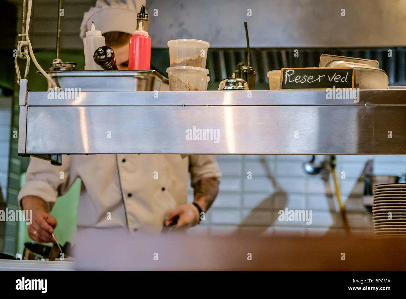 restaurant kitchen close up with Reserved table and  blurred chief cook on the background. Stock Photo