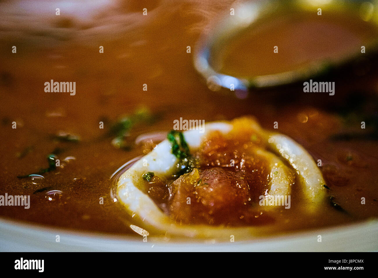 Delicious hot tomato soup with a spoon  close up. Stock Photo