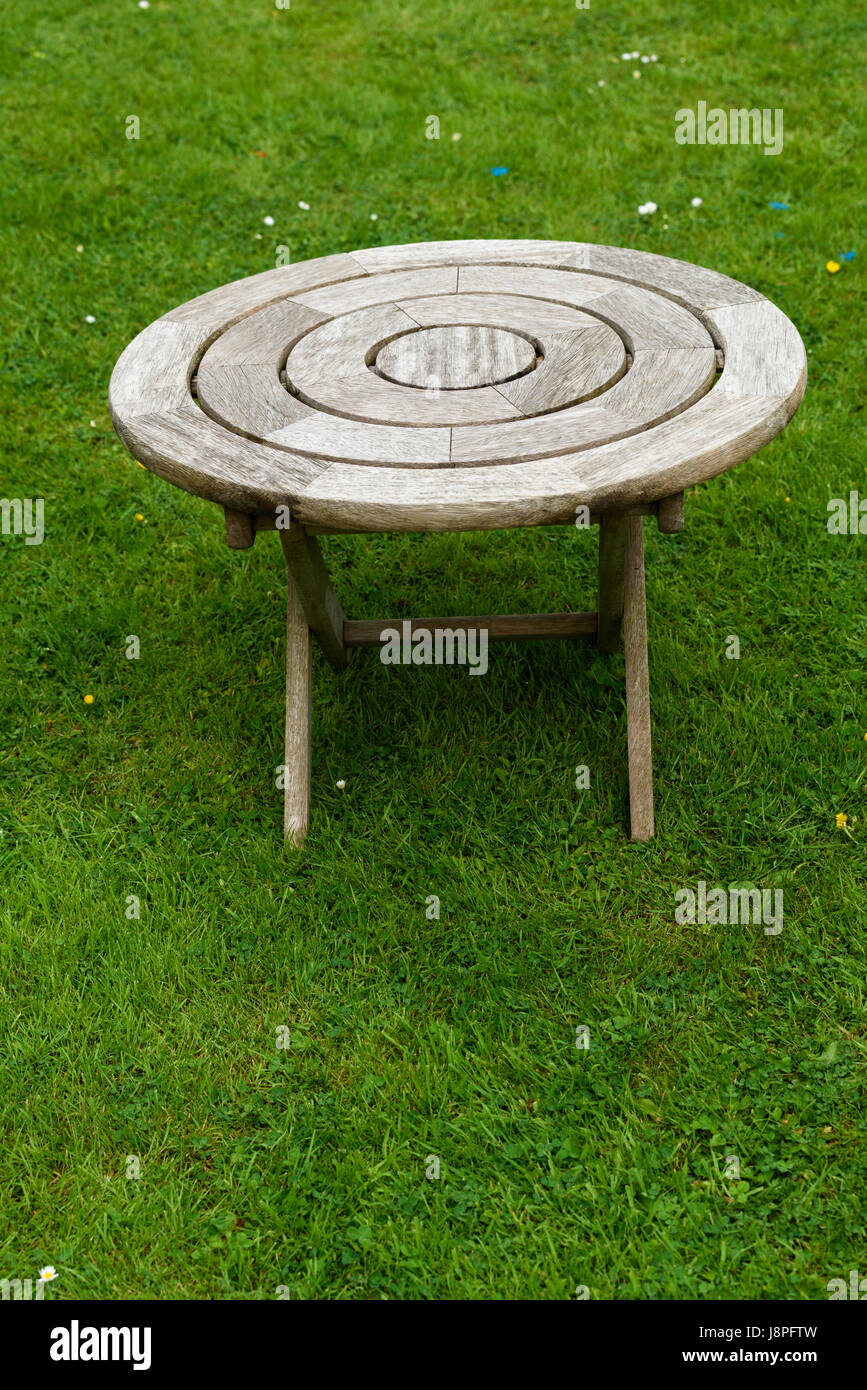 Iroko wooden round garden small side-table on a lawn. Stock Photo