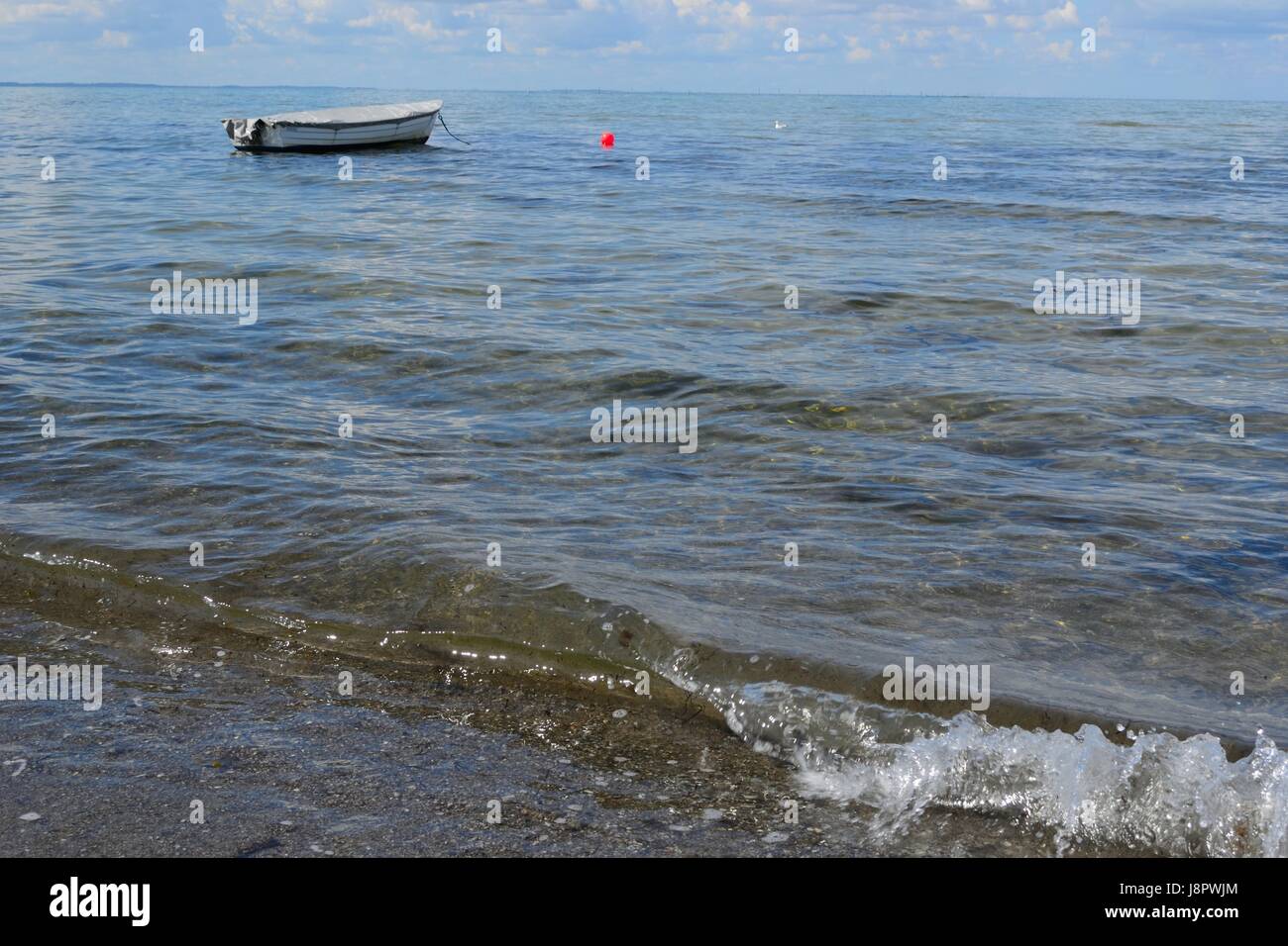 hard-made boat floating alone in the sea Stock Photo
