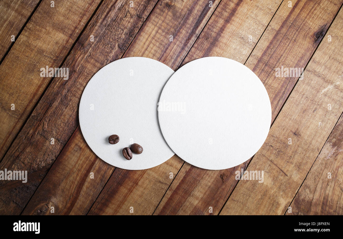 Two blank white beer coasters and coffee beans on wood table background.  Responsive design mockup. Top view Stock Photo - Alamy