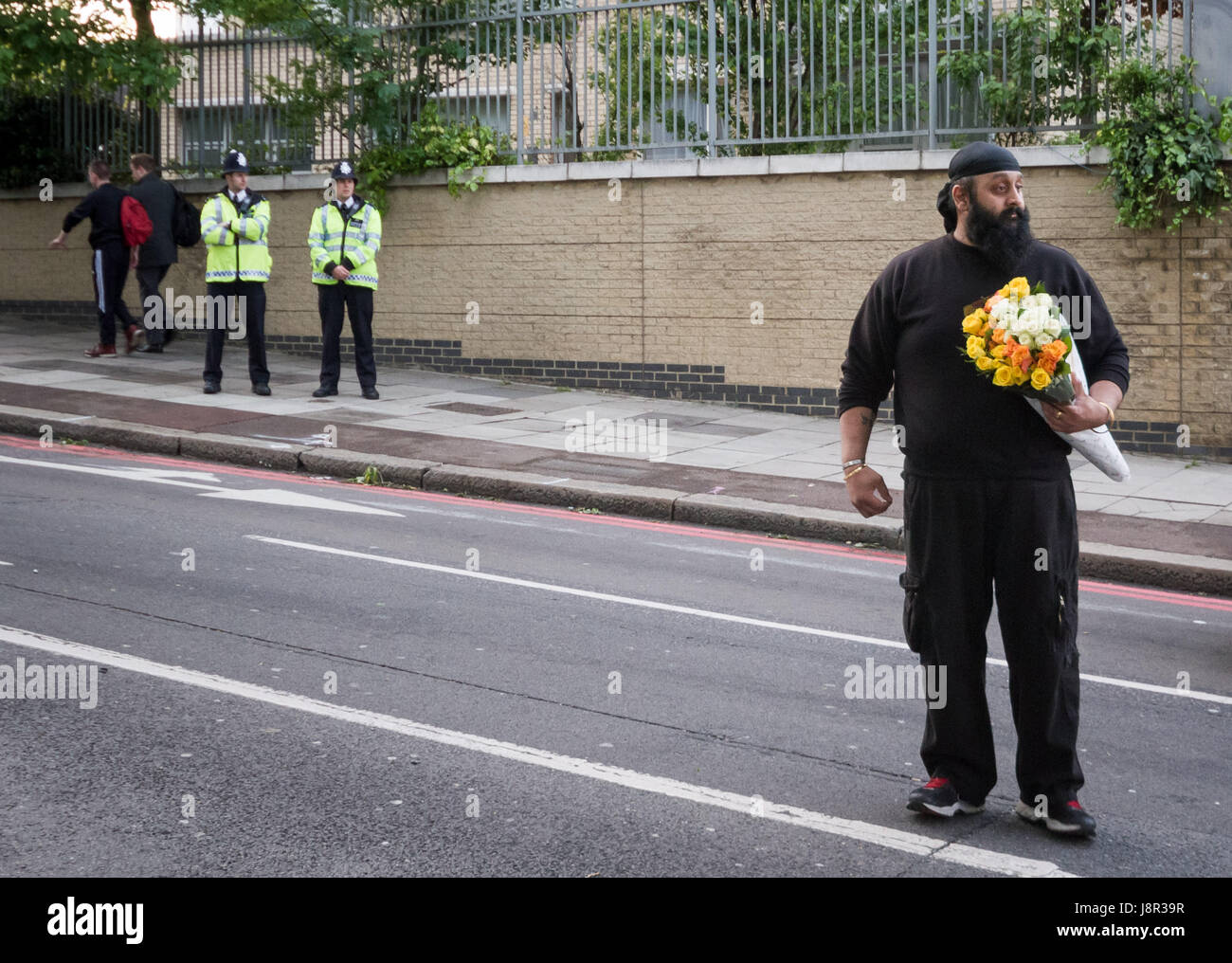 A local Sikh man crosses the road to place flowers on Wellington Street in Woolwich the day after Royal Fusilier solider Lee Rigby was murdered by Islamic extremists. London, UK. Stock Photo