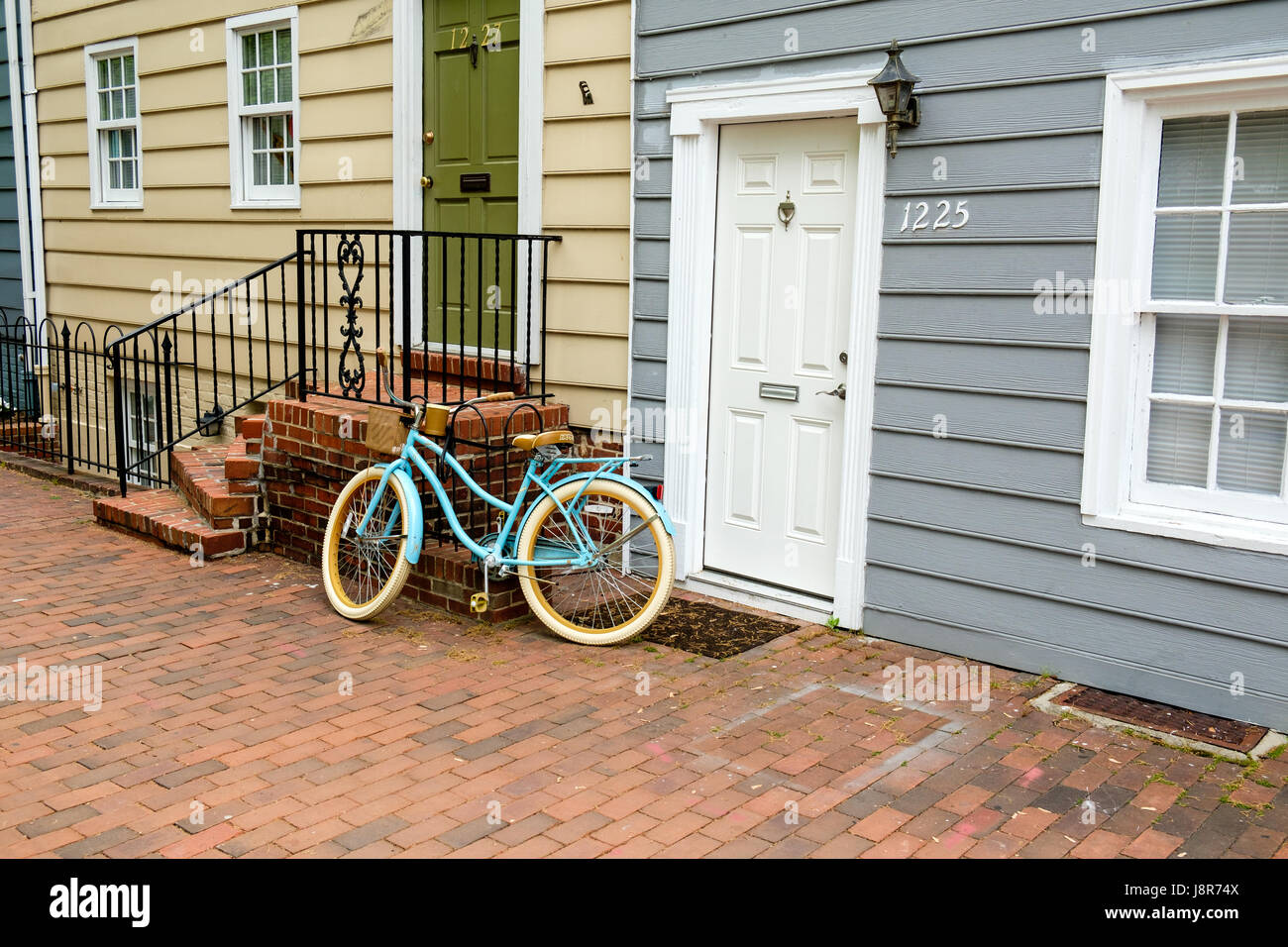 Sky blue bicycle leaning against stairs outside house in