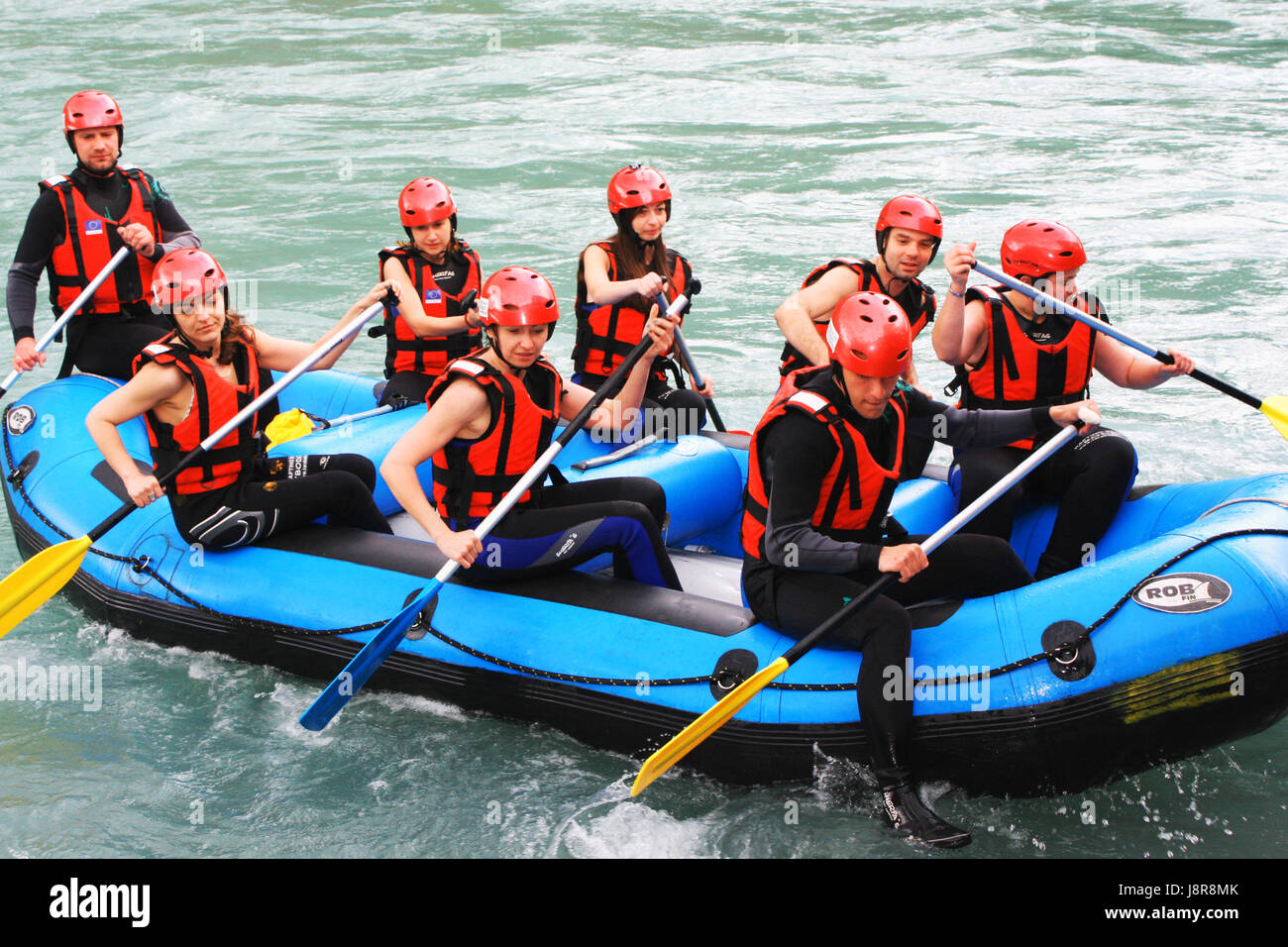 Group of happy people with guide whitewater rafting and rowing on river ...