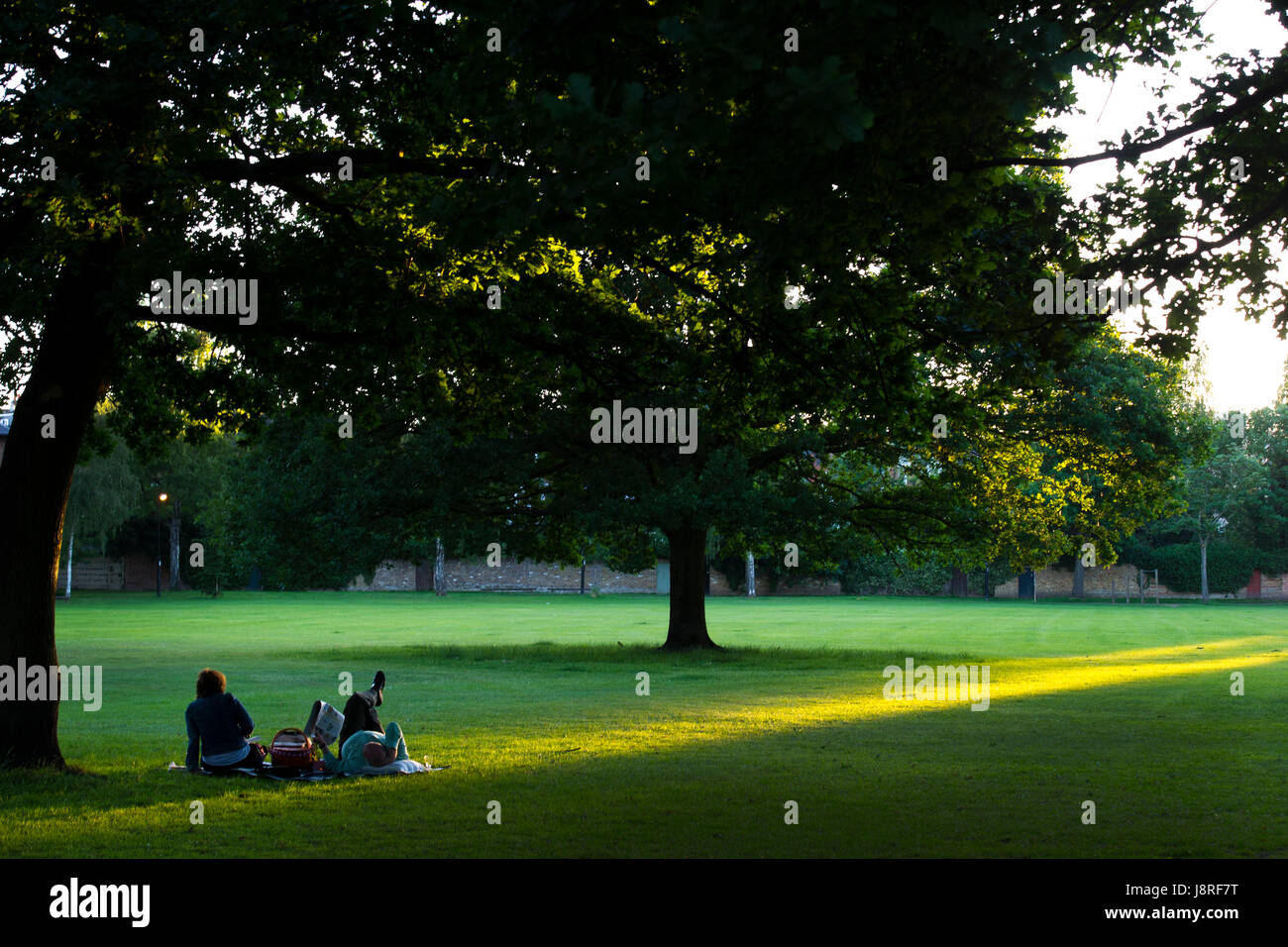 A couple enjoy a summer picnic and relax at dusk Stock Photo