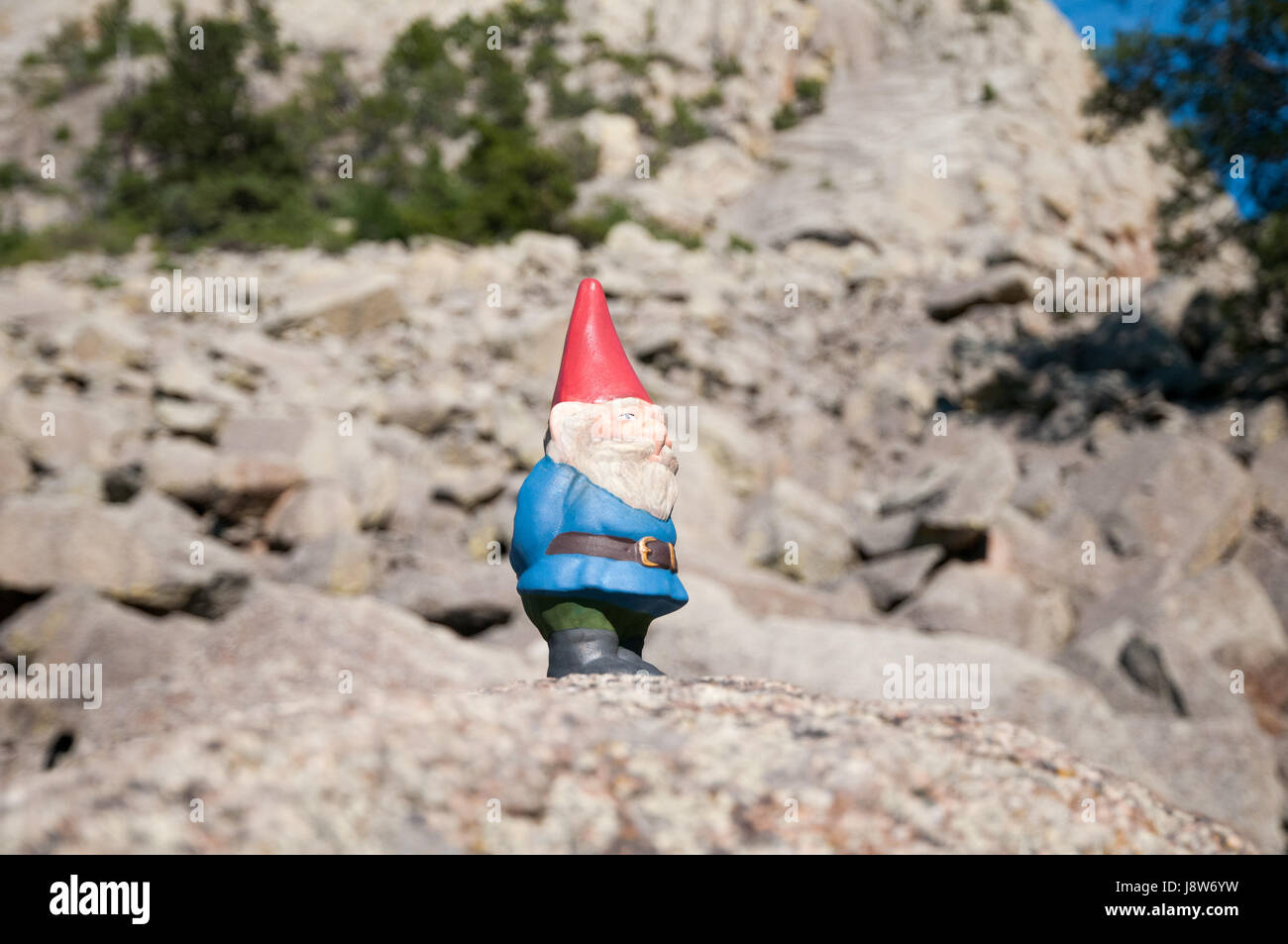 Garden gnome standing on rocks Stock Photo
