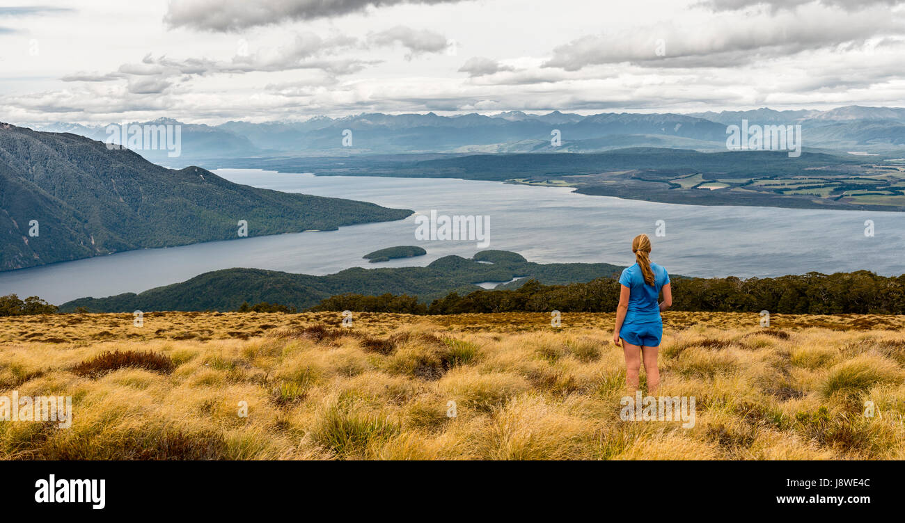 Female hiker looking at lake Te Anau and Southfiord, Kepler Track, Fiordland National Park, Southland, South Island, New Zealand Stock Photo