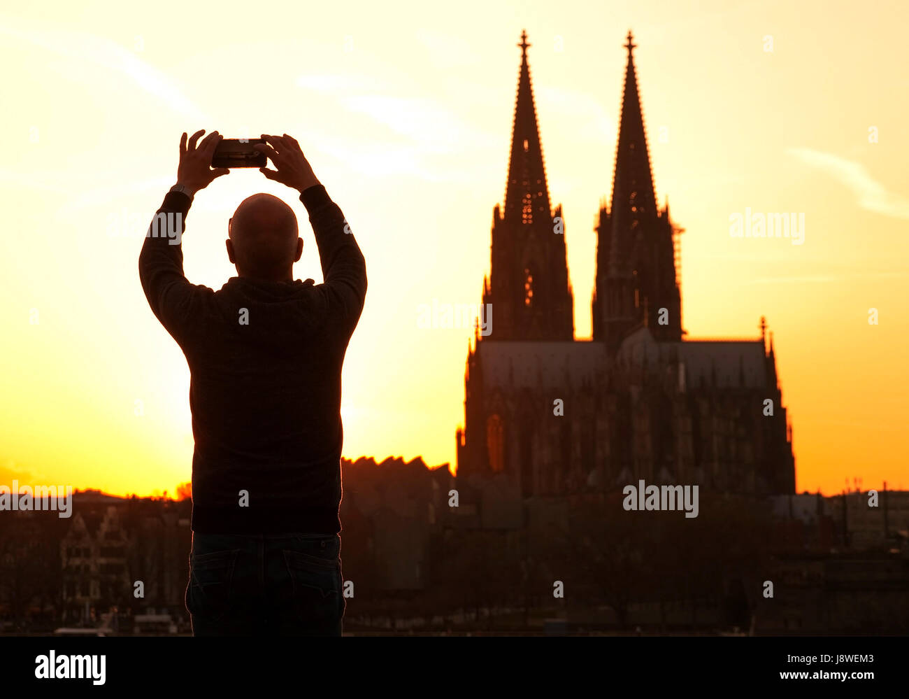 Man photographing the Cologne Cathedral at sunset with smartphone, Cologne, North Rhine-Westphalia, Germany Stock Photo