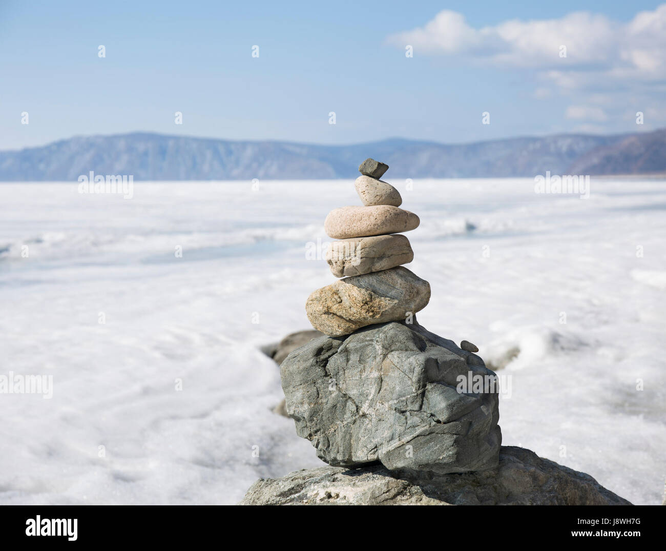 Stone tower on ice winter background. Baical landscape. Stock Photo