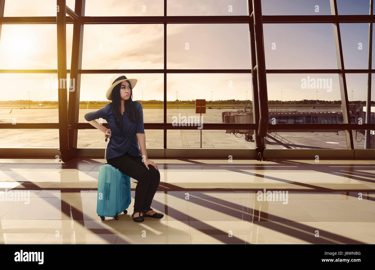 https://c8.alamy.com/comp/J8WNBG/tired-asian-traveler-woman-sitting-on-luggage-waiting-flight-at-terminal-J8WNBG.jpg