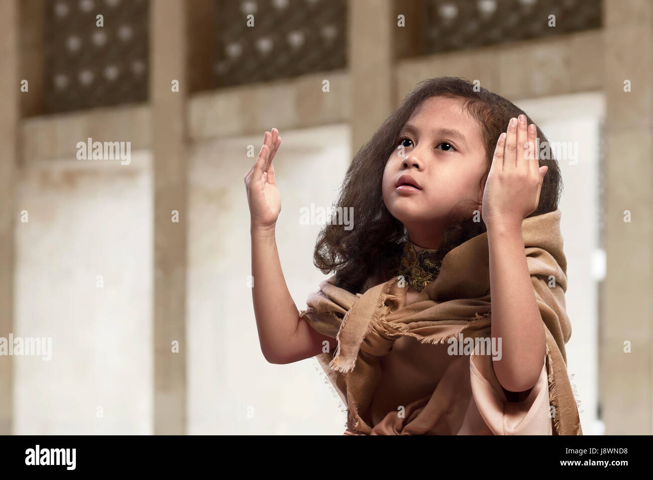 Cute asian muslim child in traditional dress praying on the mosque Stock Photo