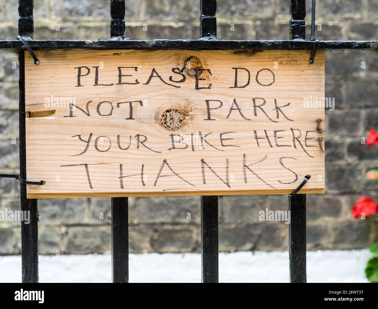 Handwritten sign requesting people don't attach their bikes to the fence Stock Photo