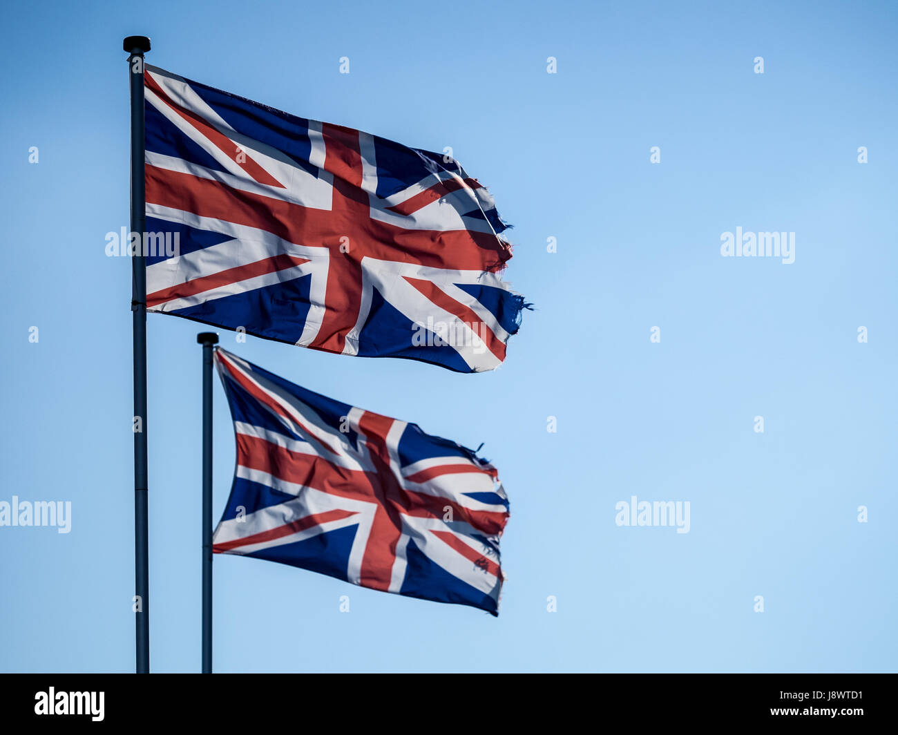 Two Union Jack flags, backlit against a blue sky Stock Photo