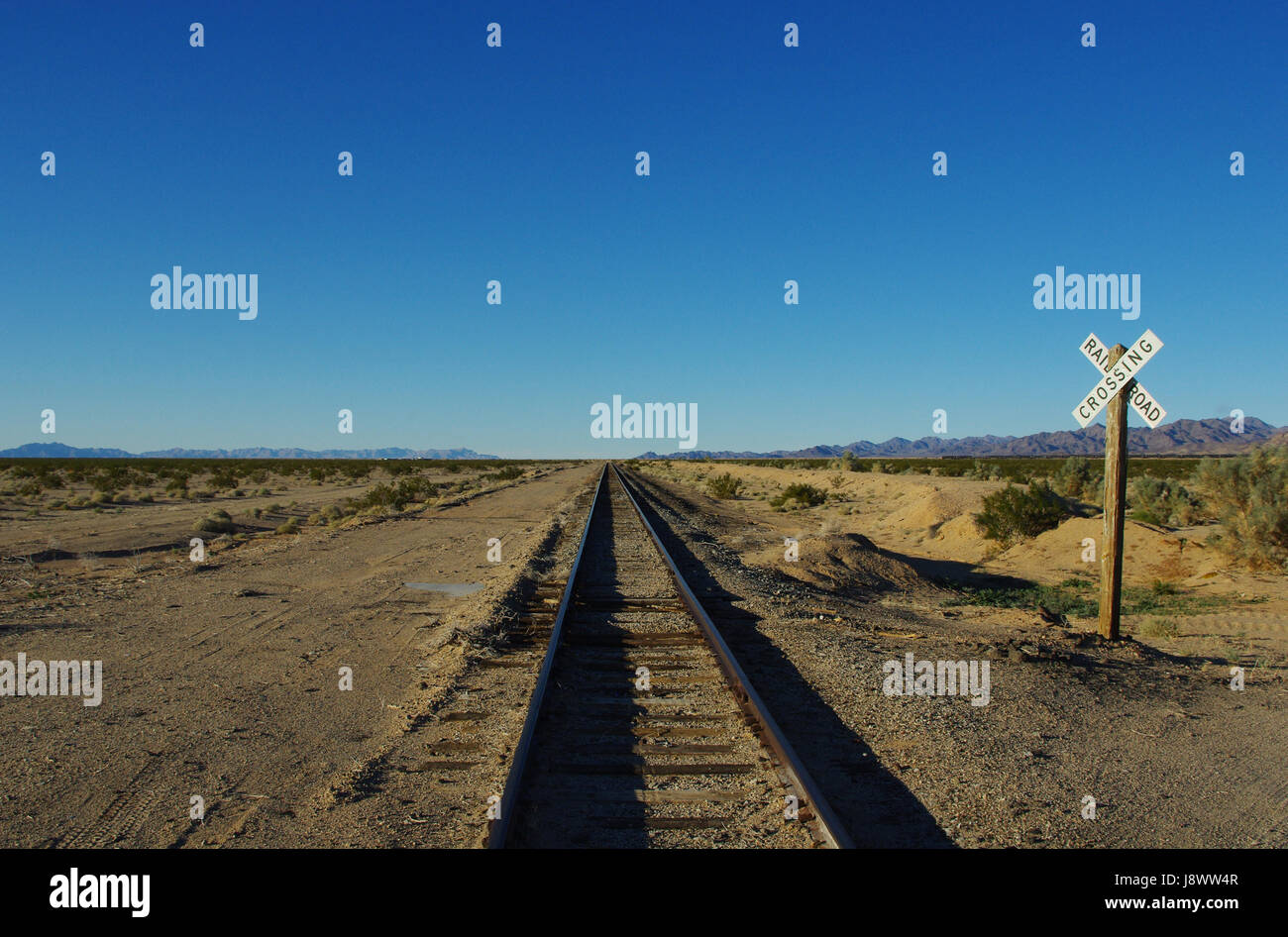 railroad crossing and track into the vastness of california desert 