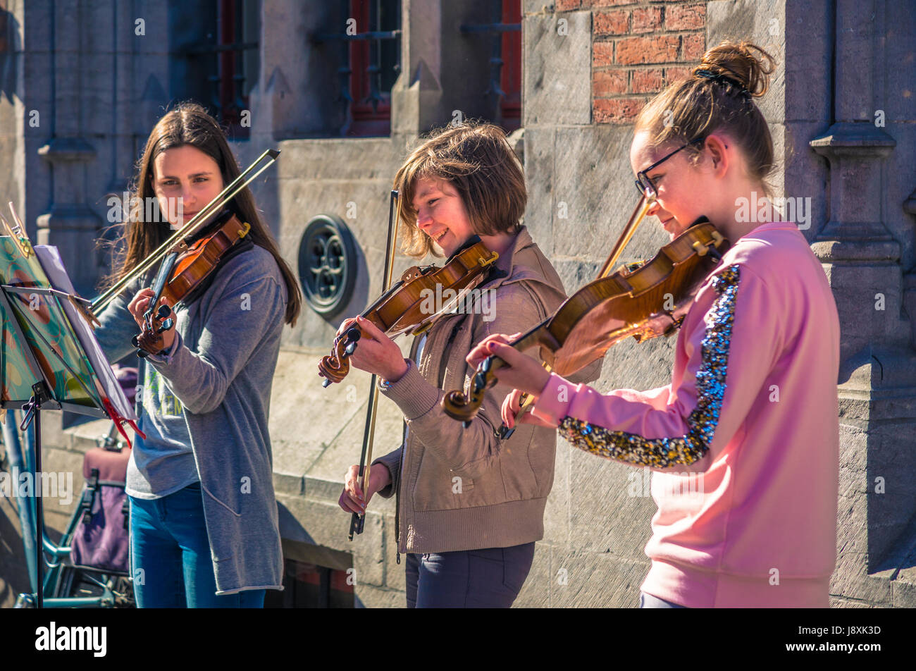 Bruges, Belgium - 11 April 2017 - Three female teen violinists play for donation on a street of Bruges, Belgium on April 11, 2017 Stock Photo
