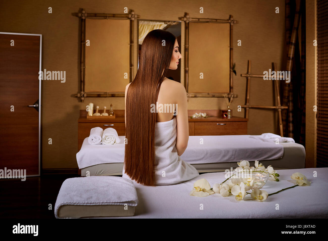 Woman with beautiful long hair sitting on massage chair in spa s Stock Photo