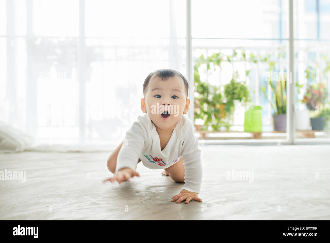 Little pretty baby girl crawling on the floor at home Stock Photo