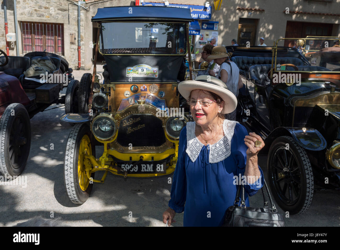 An elderly French lady and visiting vintage cars in a rural