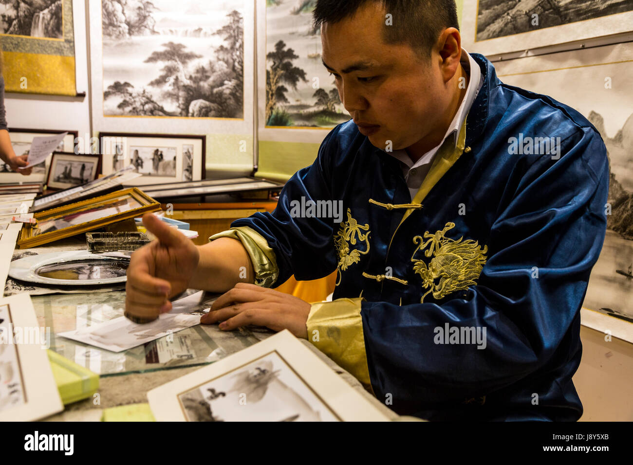 Reed Flute Cave, Guangxi Region, China.  Finger and Palm-Painting Artist at Work. Stock Photo