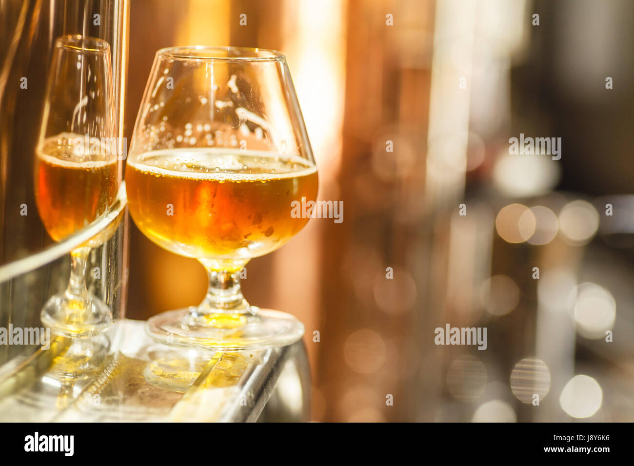 Glass with amber ale beer standing on a metal doorway of a copper lauter tun at a brewery Stock Photo