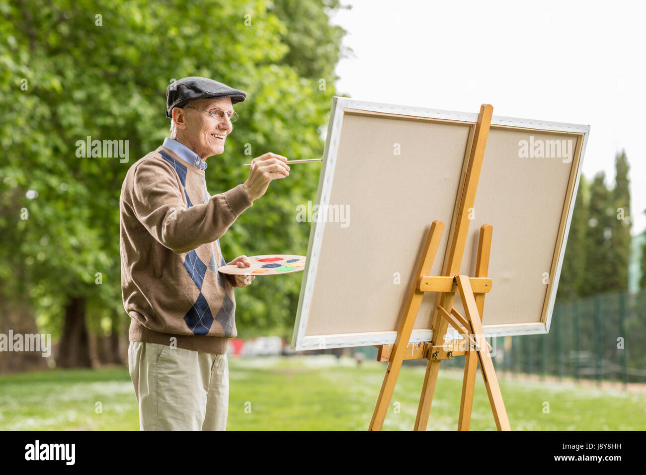 Elderly man painting on a canvas in the park Stock Photo