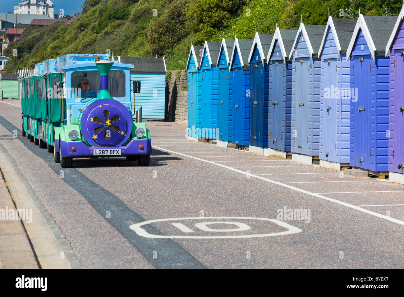 Bournemouth - Landtrain land train traveling along the promenade at Bournemouth past beach huts in May Stock Photo