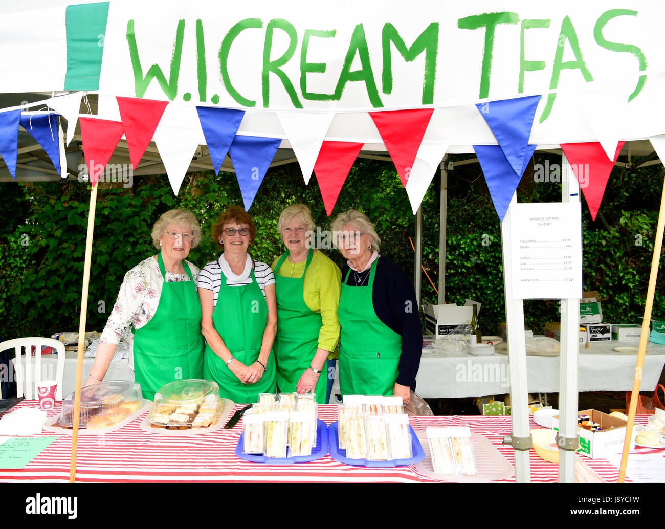 Four members of the Women's Institute (WI) on their cream tea stall/tea tent at a classic car festival, Haslemere, Surrey, UK. 28.05.2017. Stock Photo