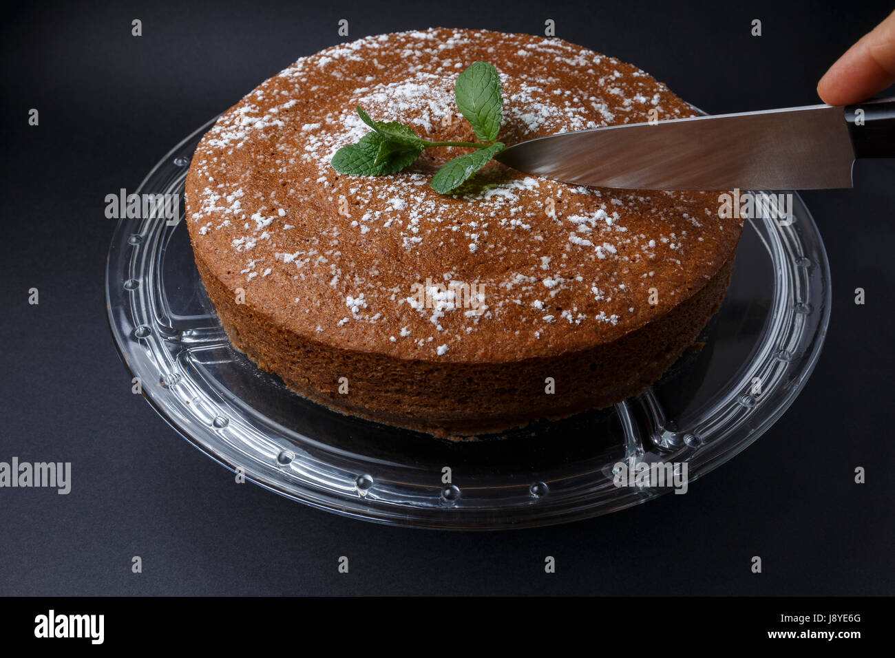 Woman Cutting A Chocolate Cake With Sugar Decoration With A Knife