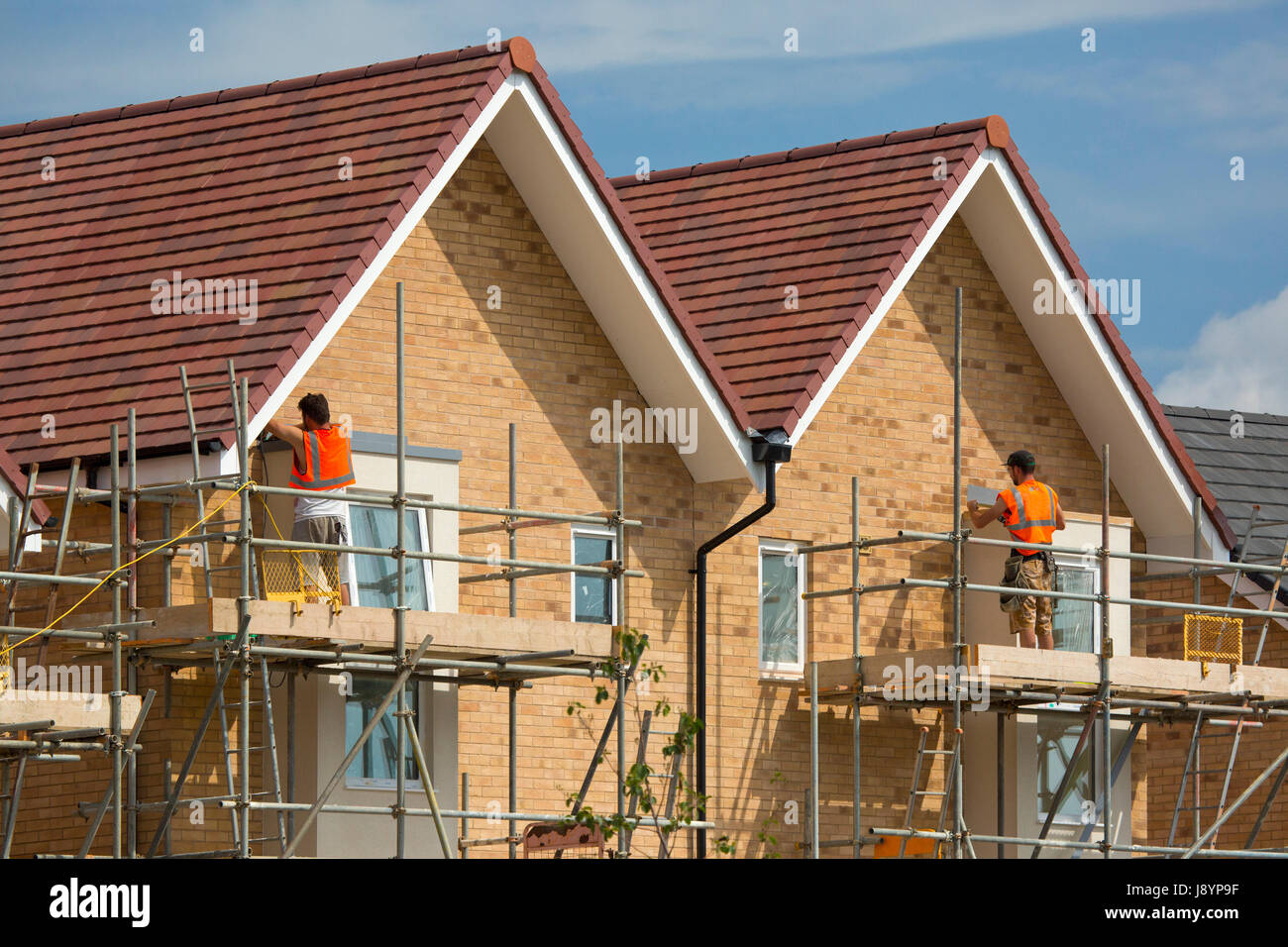 builders working on a new housing development on scaffolding Stock