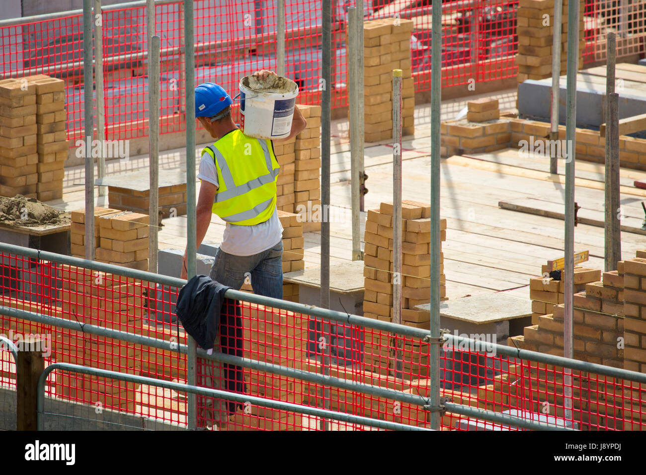 A building site worker or hod carrier or labourer carrying some cement in a bucket Stock Photo