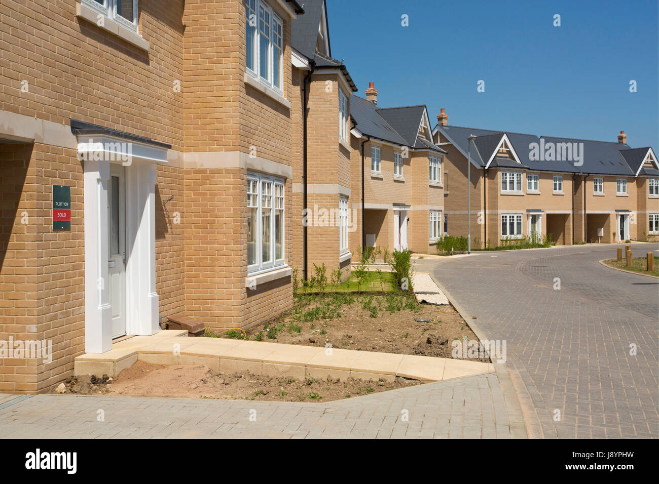 An empty street in a mostly complete new housing development, with houses sold before completion Stock Photo