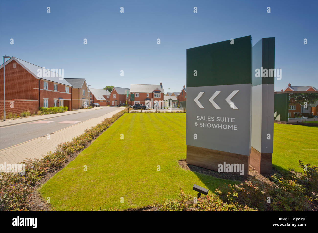 An empty street in a mostly complete new housing development, with show home and sales Stock Photo