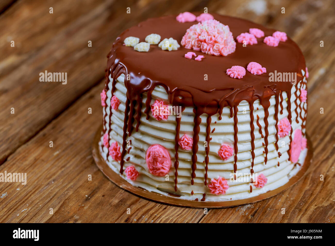 cake covered with chocolate with pink roses on the old board Stock