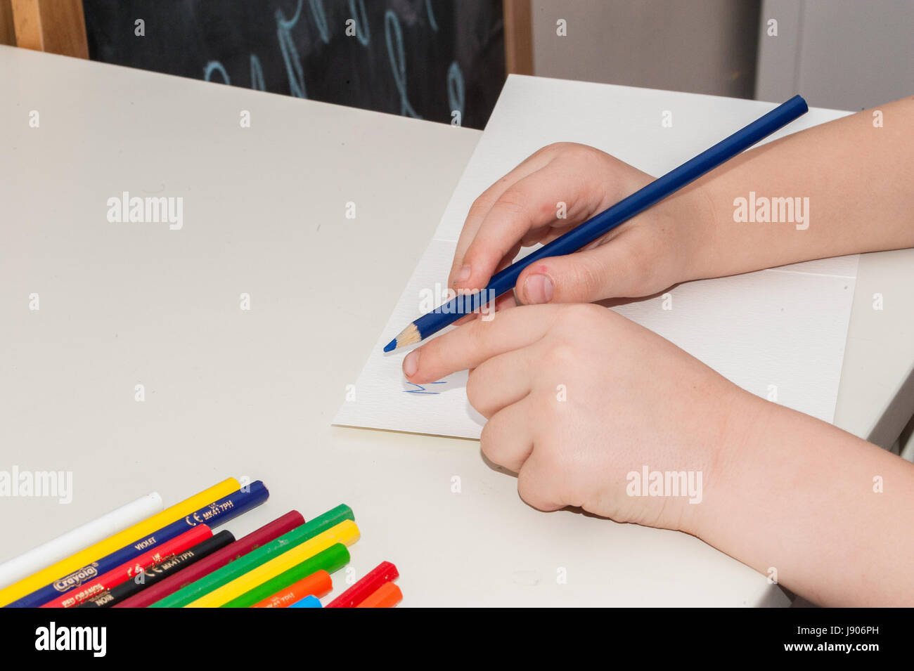 A child drawing with crayons and white paper Stock Photo - Alamy