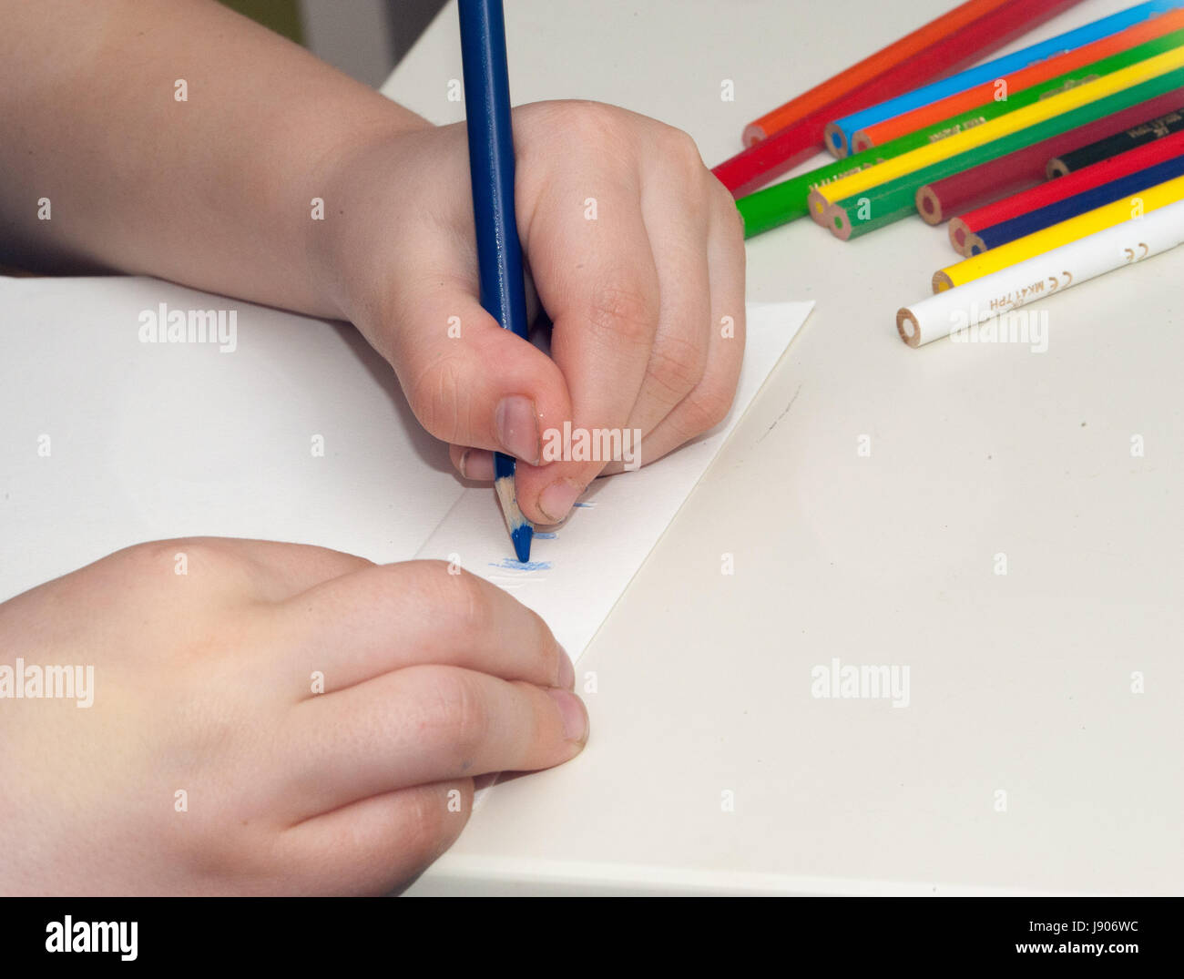 A child drawing with crayons and white paper Stock Photo - Alamy