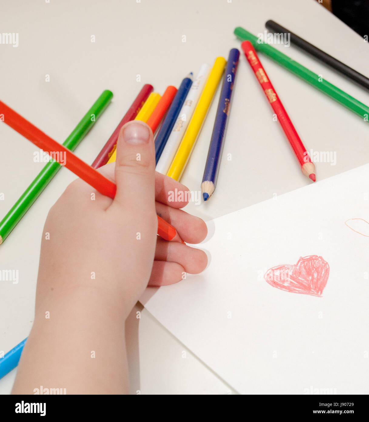 A child drawing with crayons and white paper Stock Photo - Alamy